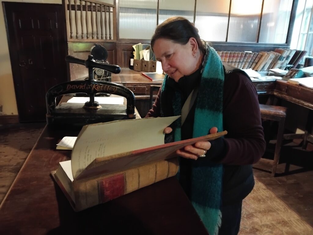 Zoe Gilbert museum report work Photo of a woman looking through an old book in a Georgian office